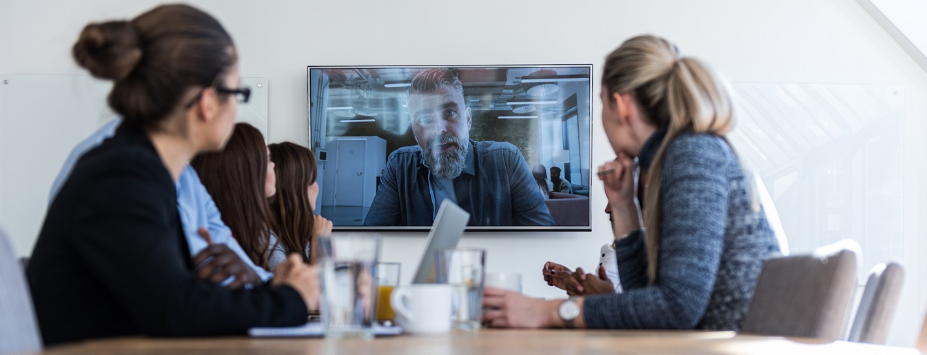 A group of people in a boardroom watching a video presentation